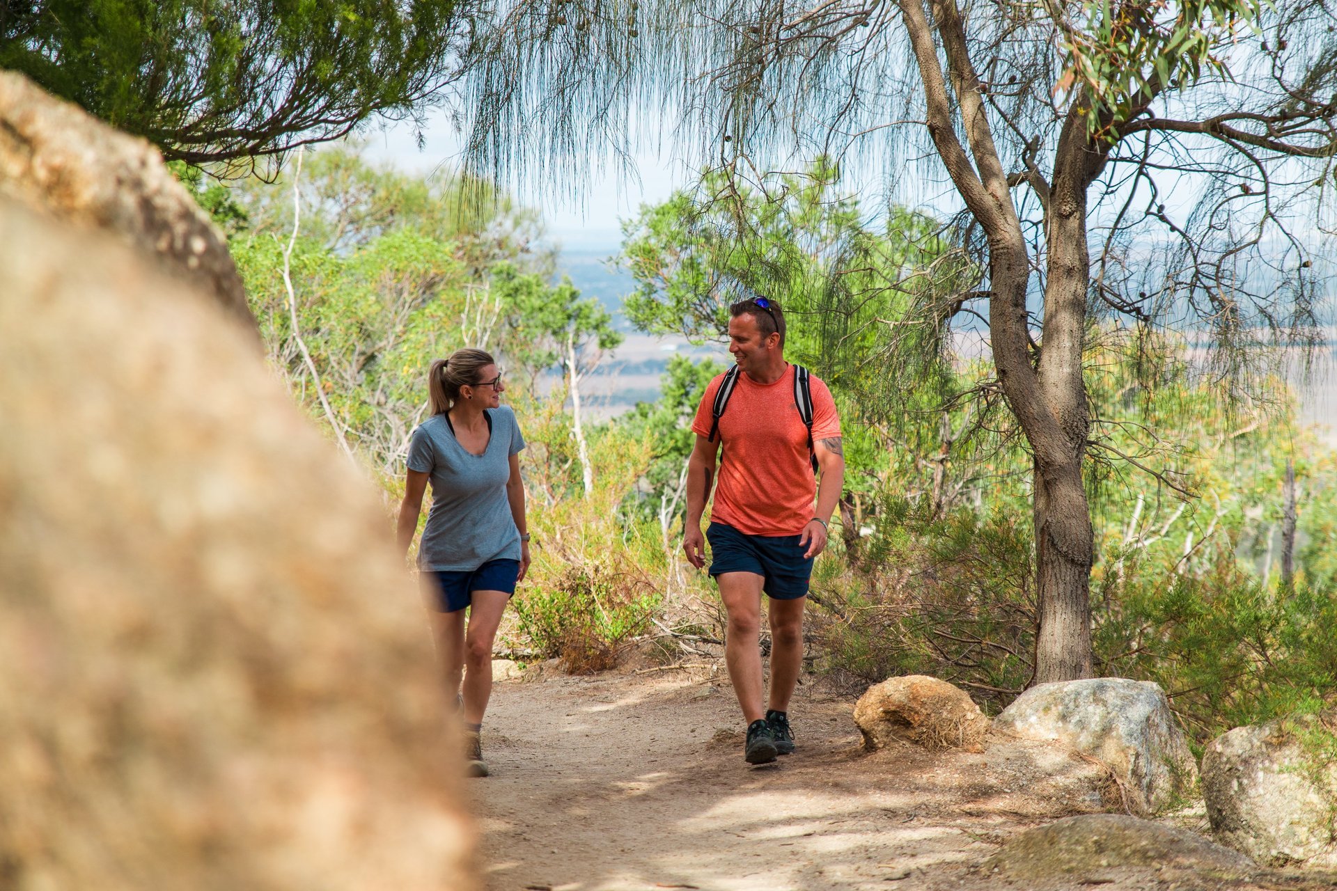 Two people hike the You Yangs Regional Park on a sunny summer day.