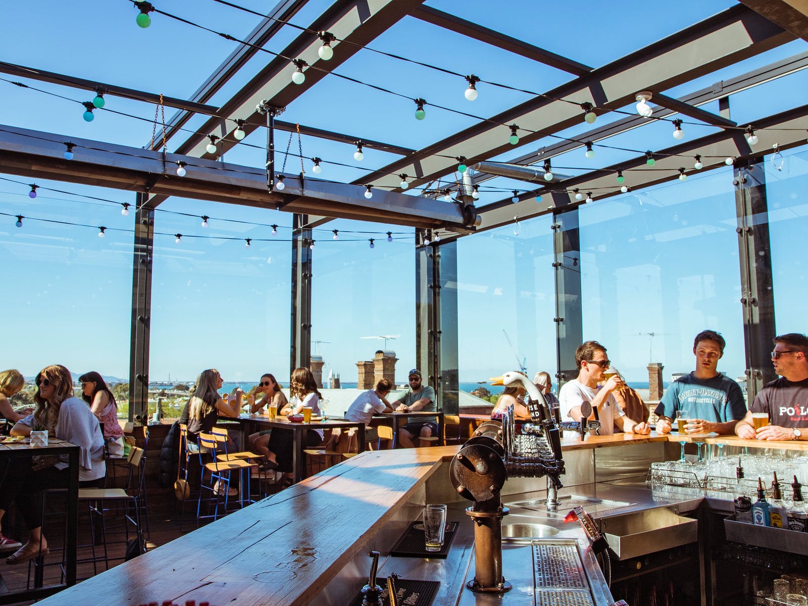 A photo of Murphys rooftop bar. People sit at tables with blue skies beyond.