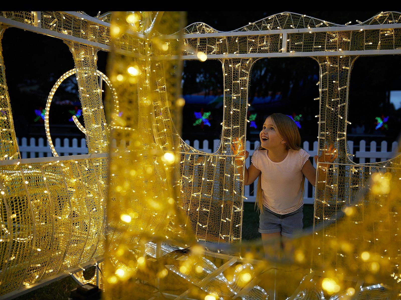 A child looks inside a lit-up house frame at Adventure Park Christmas Festival of Lights.