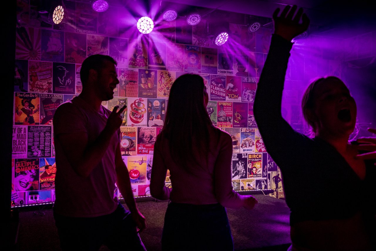 Three people dancing under purple light