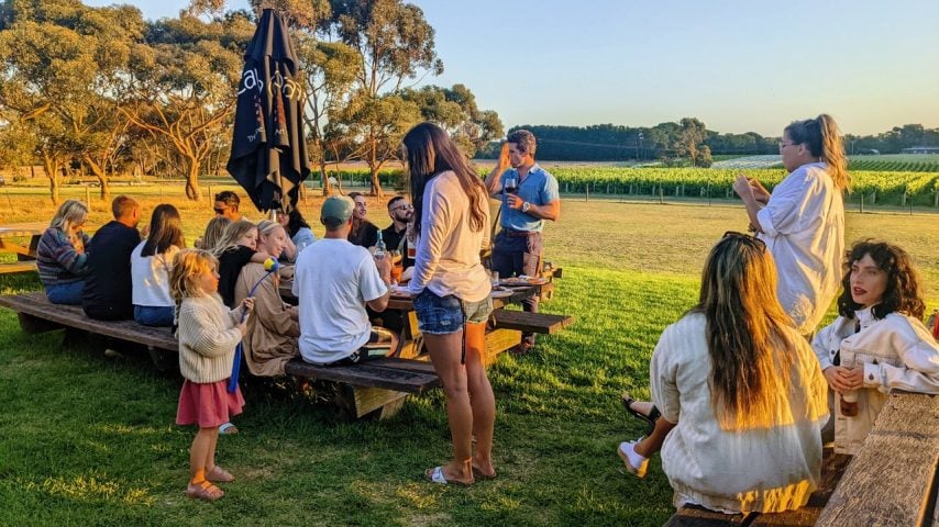 People sit, drink and eat at outdoor picnic tables at FarmDog Brewing