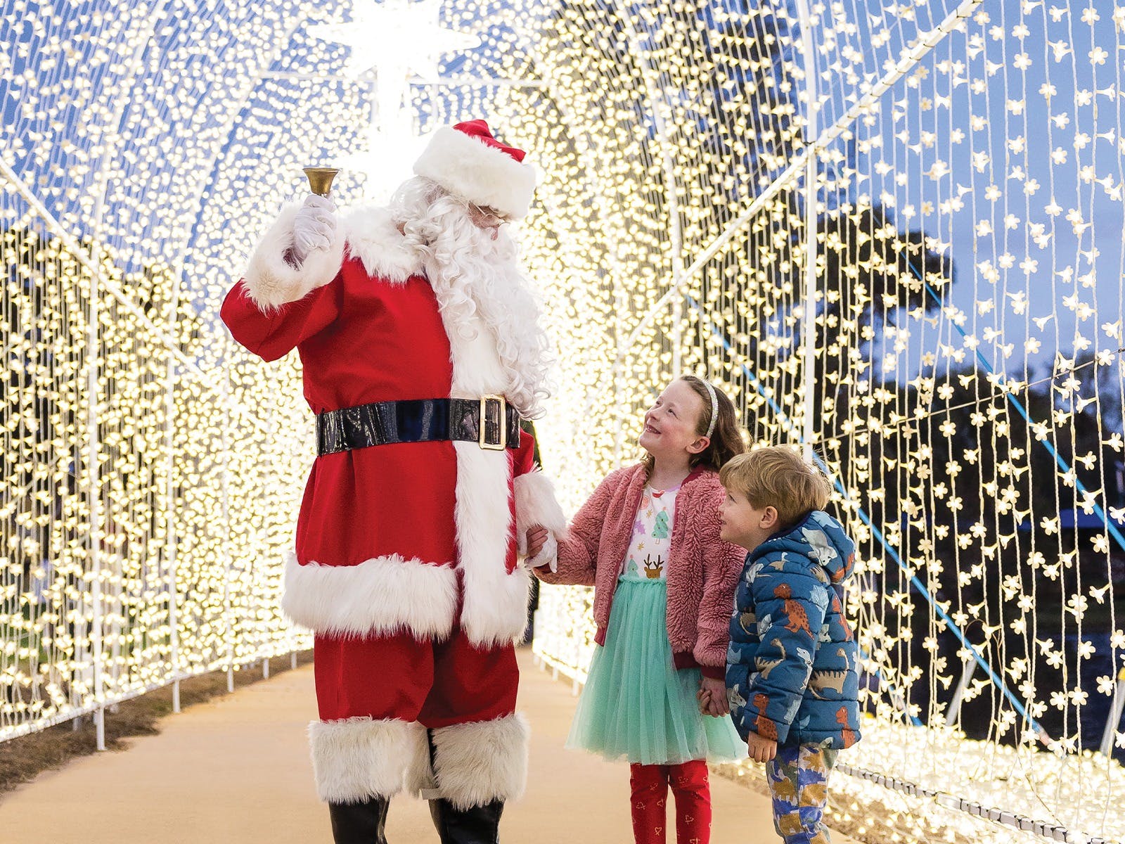 Two children hold hands with Santa in a light tunnel at Adventure Park's Christmas Festival of Lights.