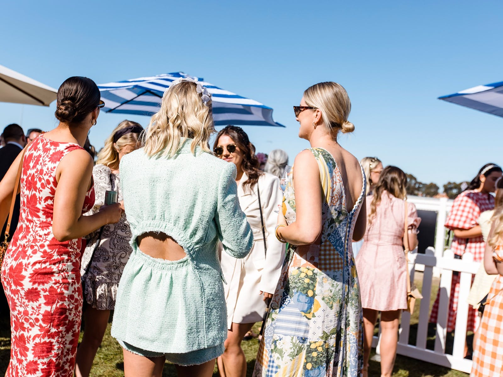 Group of females dressed up at the racing event with blue sky
