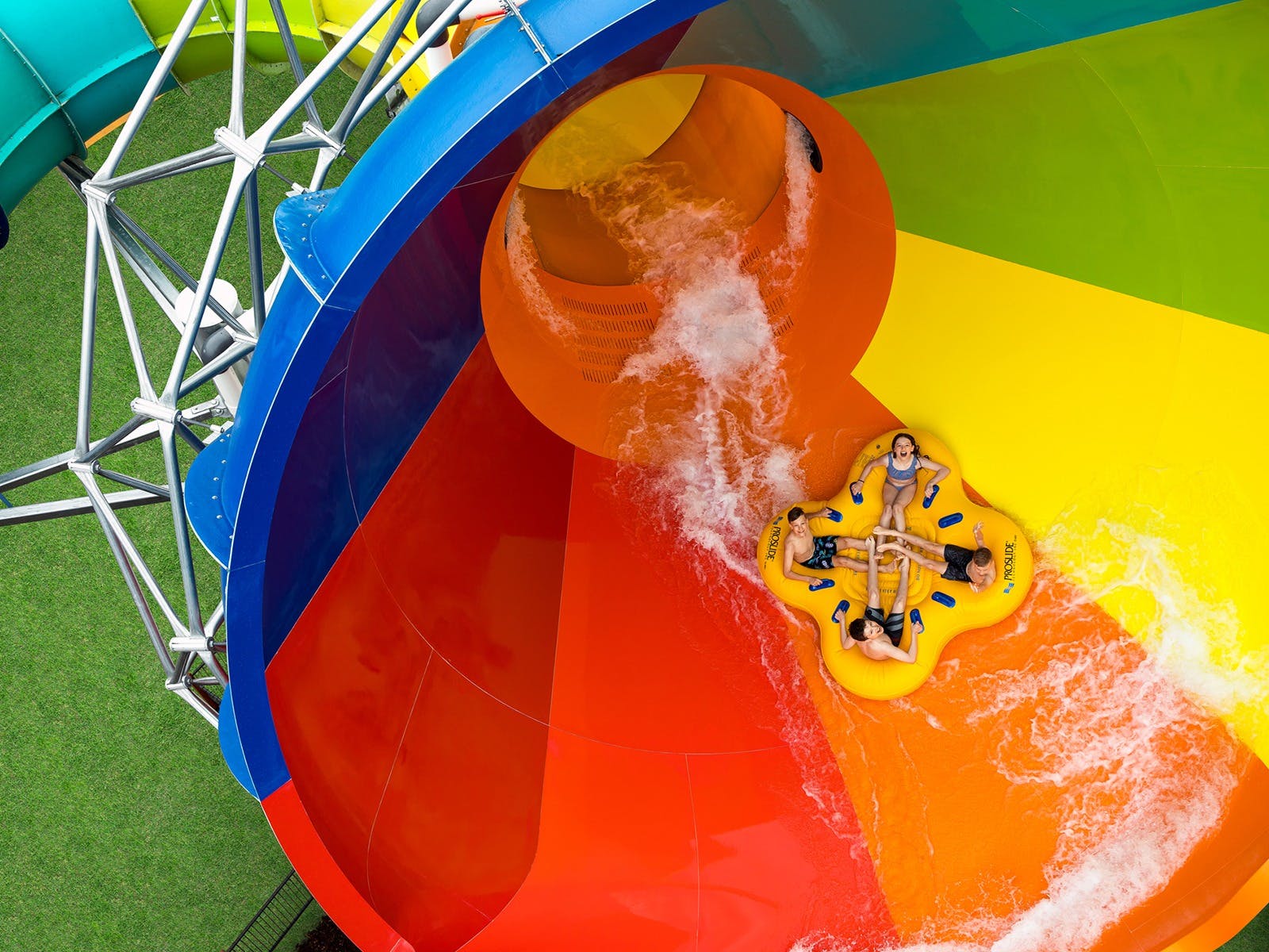 A group of people on an inflatable ring slide down a waterslide.