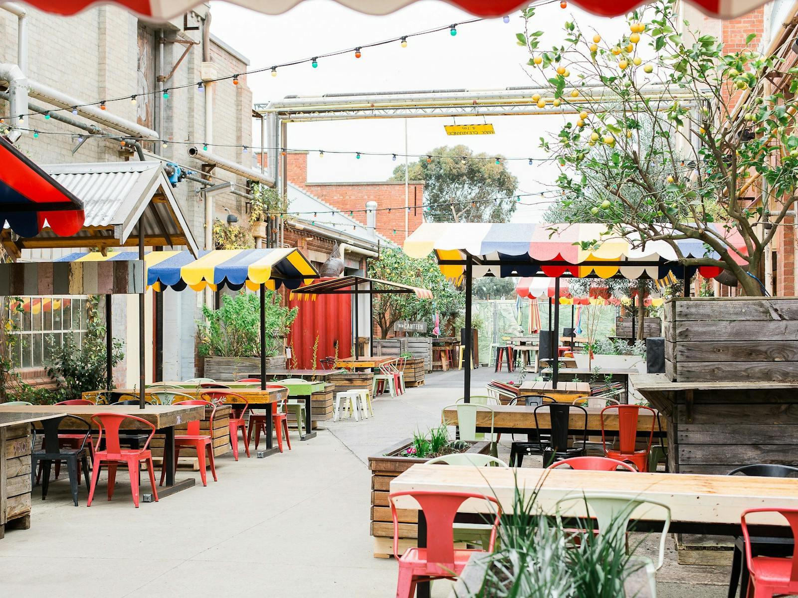 Little Creatures outdoor dining space, with rustic tables and colourful umbrellas in a lane.