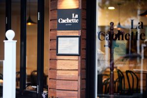 Entrance to restaurant with plaque 'La Cachette'