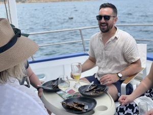 Passengers on boat with plates of mussels and champagne